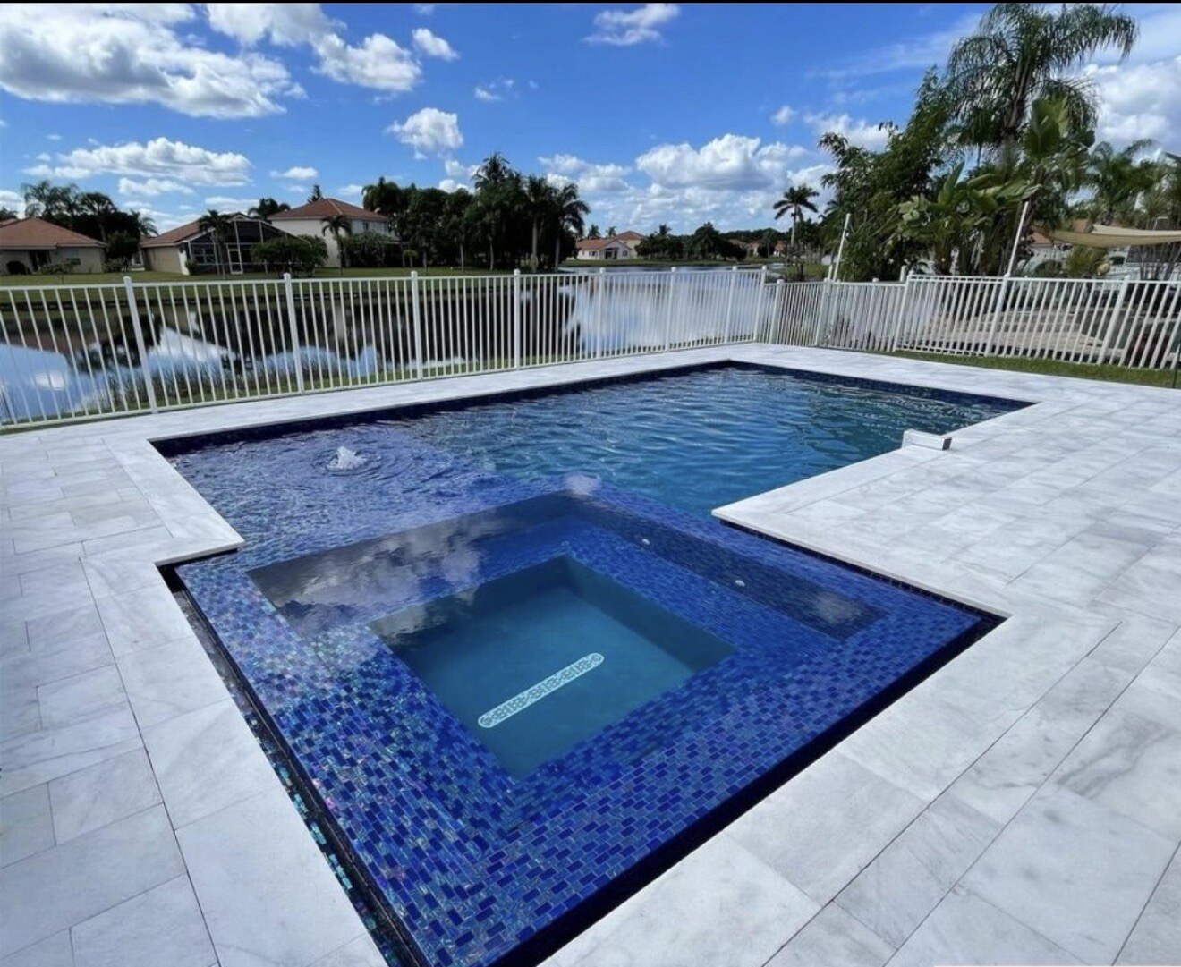 Completed geometric Orlando pool with blue tile, light deck, lawn and a screened safety fence.