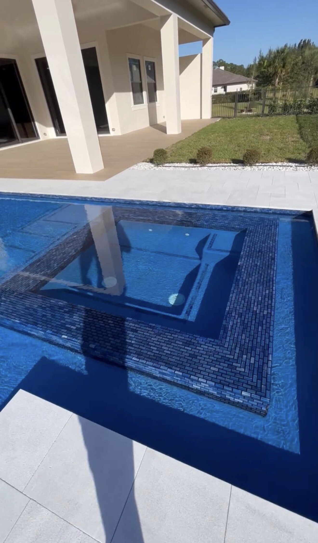 Closer view of the completed Orlando pool beside the home, showing blue waterline tile and light pavers.