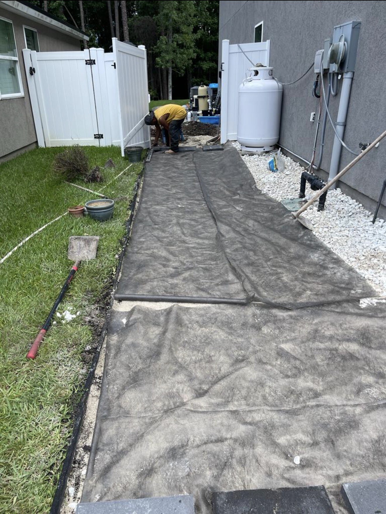 Construction progress photo of a paver walkway leading across the Mandarin backyard.