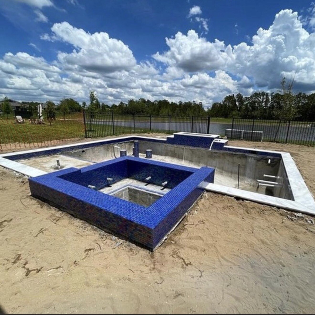 Orlando pool during construction, showing the unfinished pool shell and blue-tiled spa or step area.
