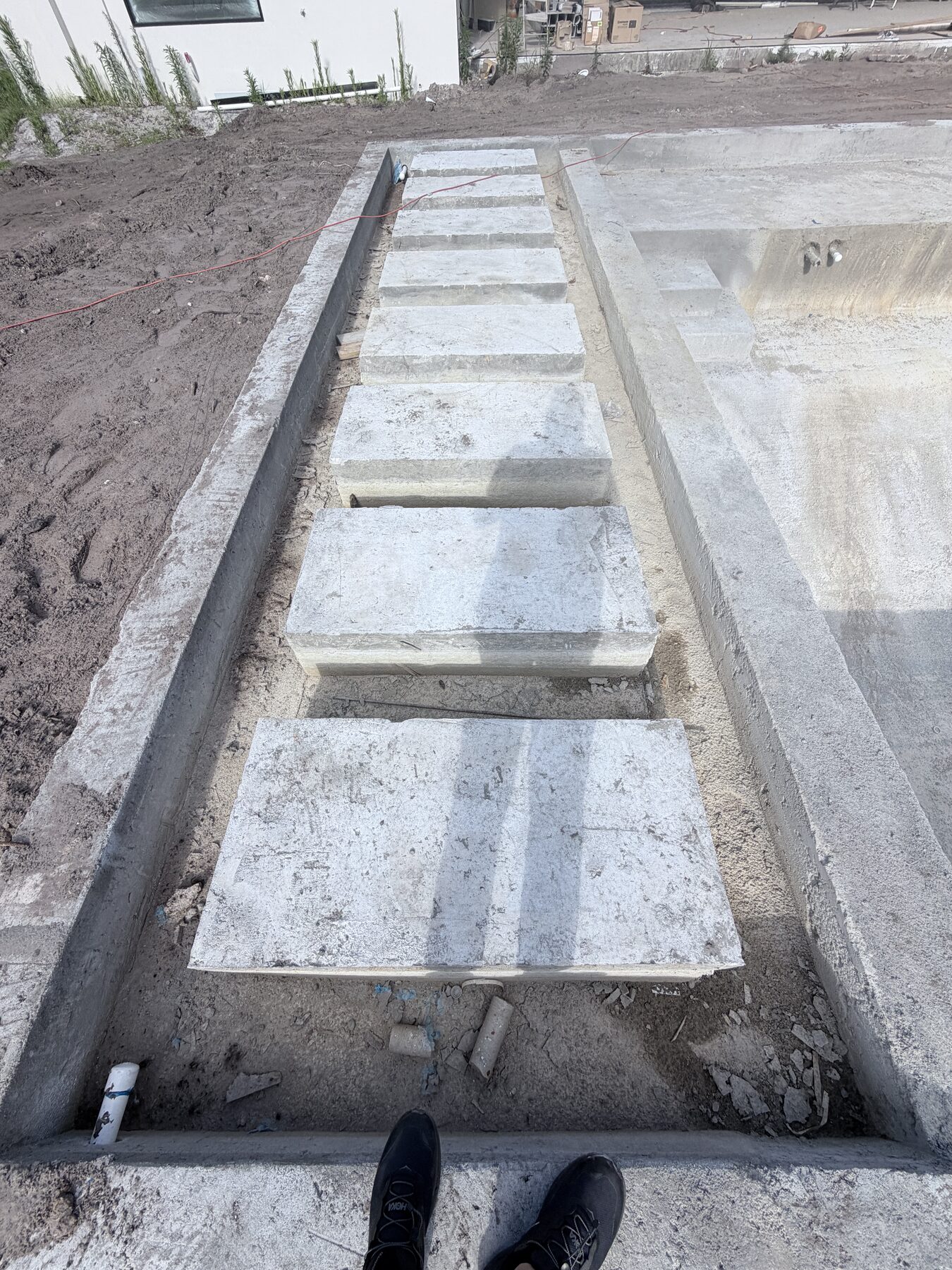 Close view of unfinished concrete pool steps beside the pool shell