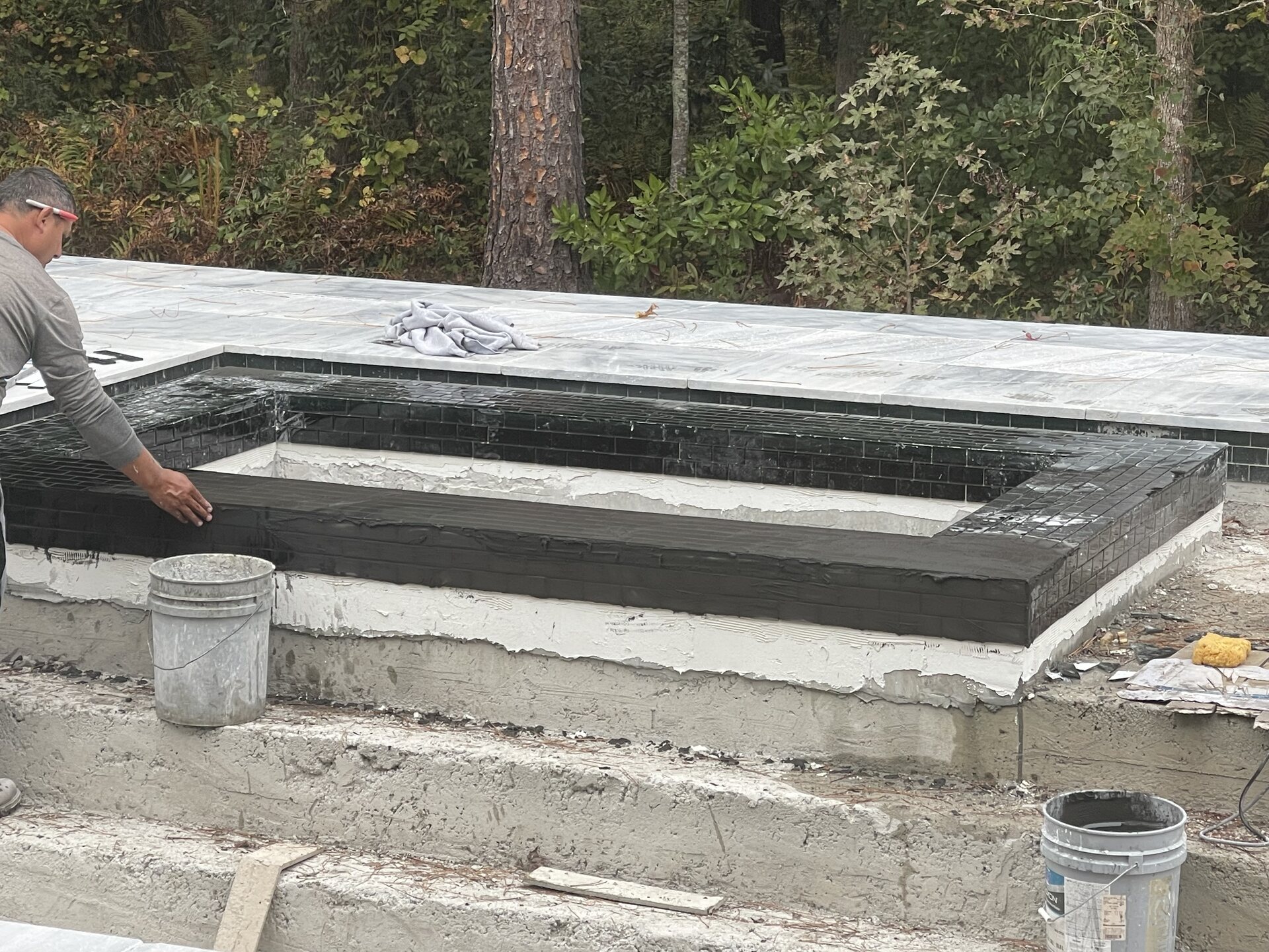 Construction crew working along the pool deck and retaining-wall area.