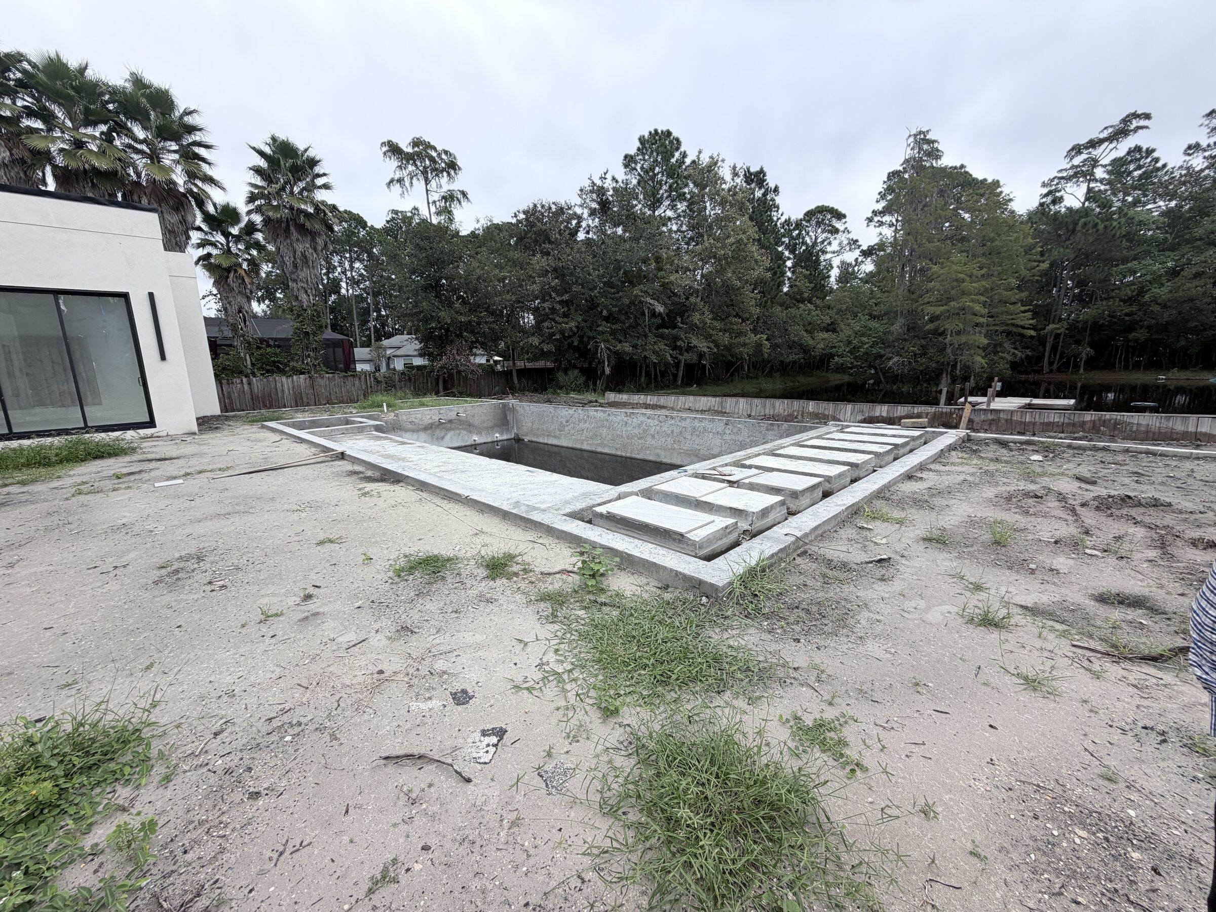 Wide overview of the unfinished pool shell and backyard work area