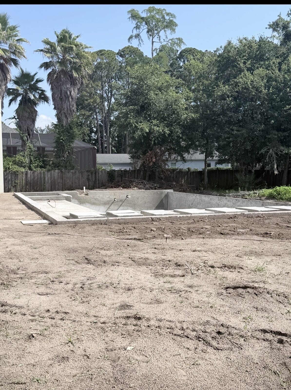 Vertical view of the unfinished pool edge set into a residential backyard