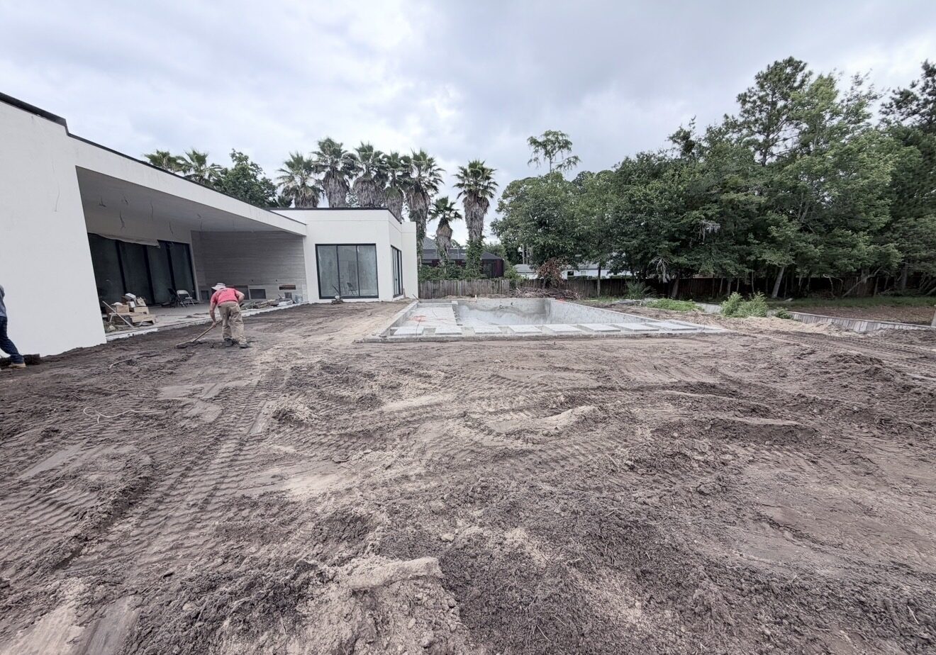 Wide residential backyard view with the unfinished pool shell and site grading underway